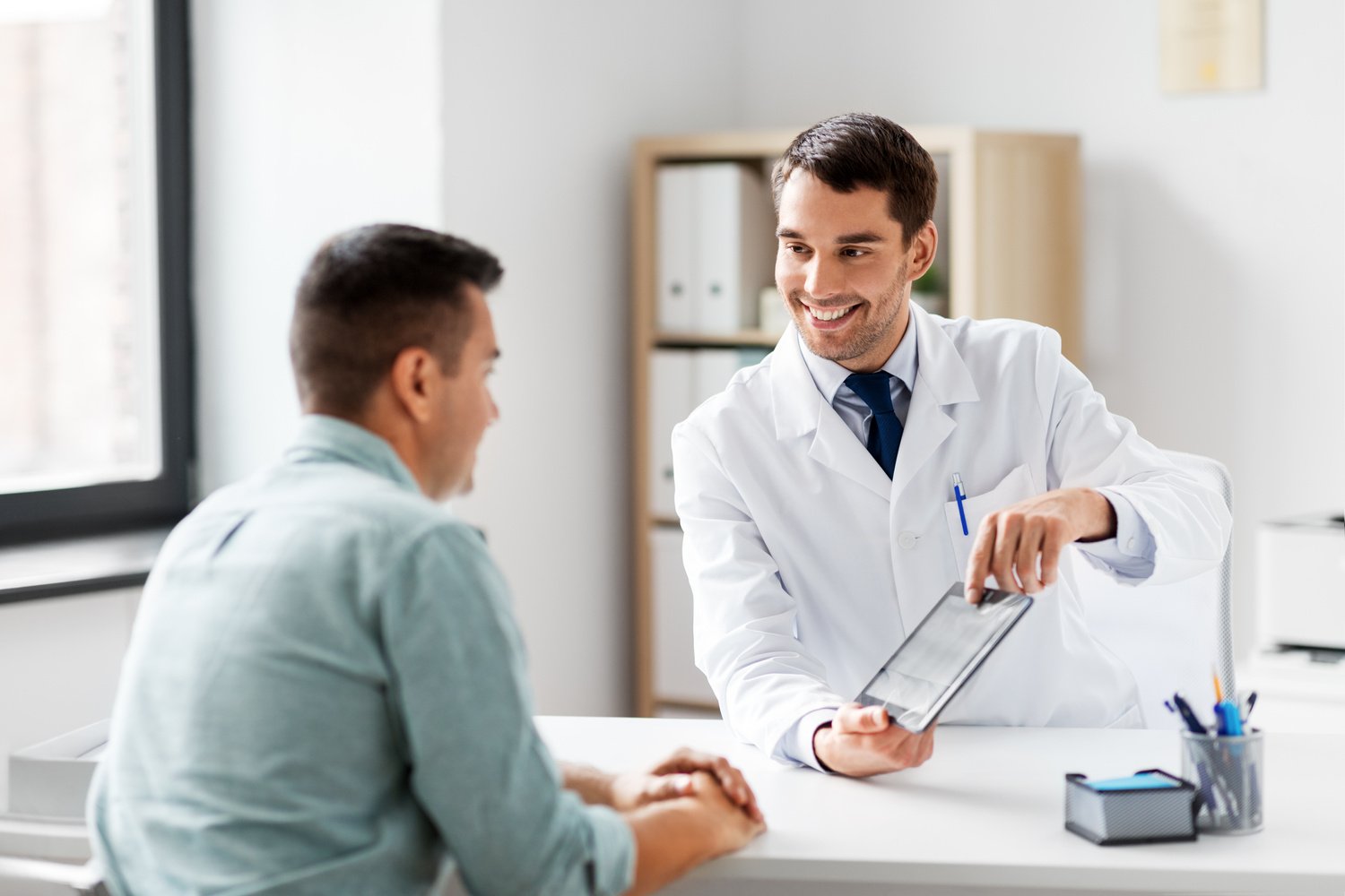 Doctor with Tablet Computer and Patient at Clinic